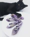 Amethyst pipes on a white background. A Black cat reaches for the pipes with her claws extended