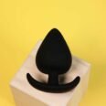Silicone black spade butt plug with comfort shown on wooden block