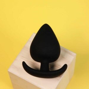 Silicone black spade butt plug with comfort shown on wooden block