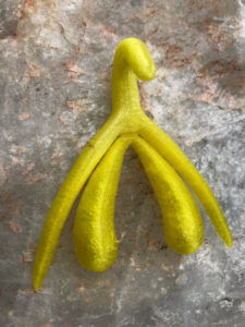 Yellow 3D printed clitoris on a clear crystal stone background
